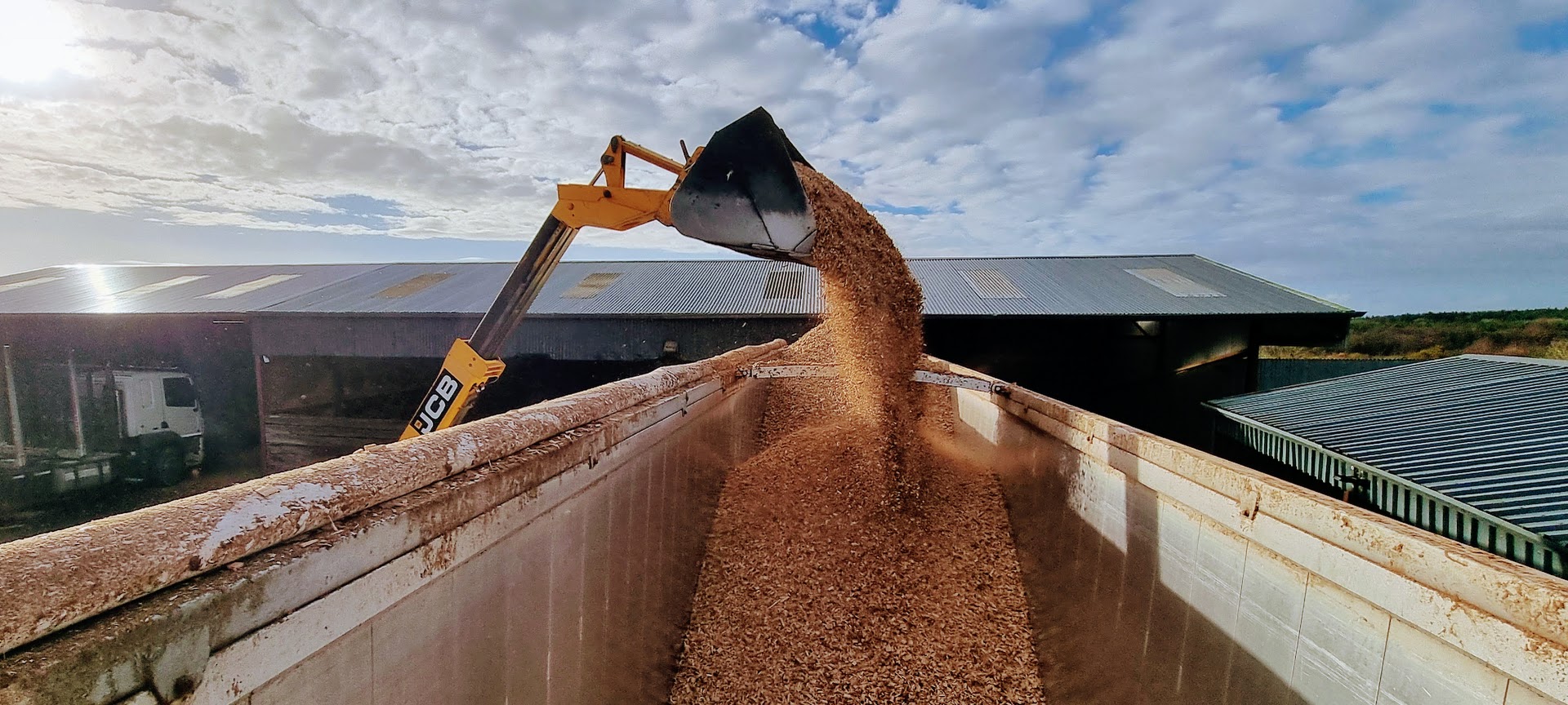 Loader dispatching wood chip into a trailer for delivery
