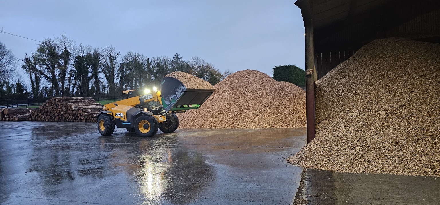 Loader handling wood chip during commercial biomass processing